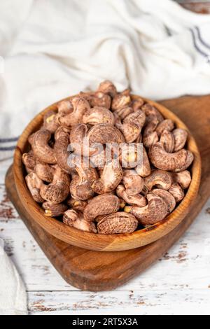 Cashews with shell in wood bowl. Shelled cashew on white wood background Stock Photo