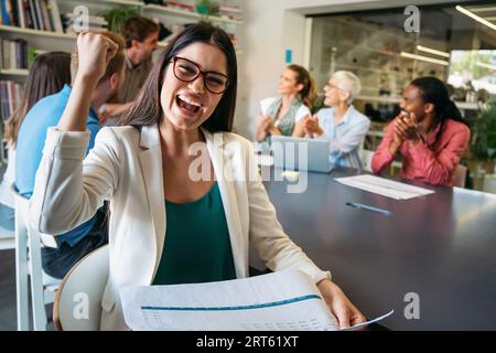 Smiling diverse colleagues gather in boardroom brainstorm discuss financial statistics together Stock Photo