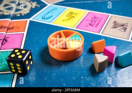London, UK - 07 April 2019: A board games tournament - Close-up of classic board game Trivial Pursuit with black die and colored plastic pieces of dif Stock Photo