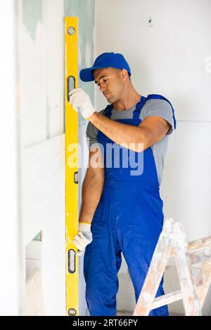Repairer using spirit level on wall, working on home improvement Stock Photo
