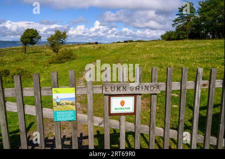 'Keep the gate closed'. Sign on a wooden gate for the entrance to a pasture where cattle is grazing on Jomfruland island in Telemark, Norway. Stock Photo