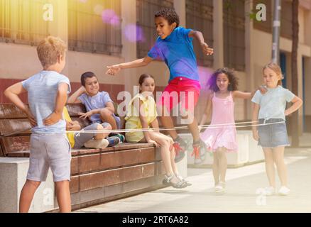 Mexican boy playing rubber band jumping game with friends Stock Photo