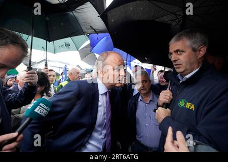 Tanaiste Micheal Martin (centre) listens to farmers protesting outside the Horse and Jockey Hotel in Thurles, Co. Tipperary, as he arrives for an Fianna Fail party event. Picture date: Monday September 11, 2023. Stock Photo