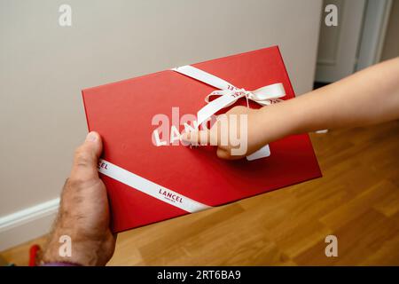 Paris, France - Aug 25, 2023: A toddler excitedly points out the Lancel logo on a gift box to an adult. Stock Photo