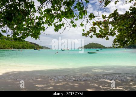 Colorful boats and transparent water in the lagoon of Port Launay beach, Mahé island, Seychelles Stock Photo