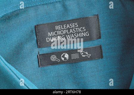 Clothing label saying 'Releases microplastics during washing'. Concept for synthetic clothing fiber pollution problem Stock Photo