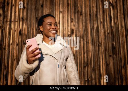 Outdoor portrait of happy african-american woman. She is messaging on smartphone. Stock Photo