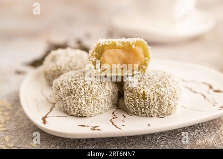 Japanese rice sweet buns mochi filled with pandan jam and cup of green tea on brown concrete background. side view, close up, selective focus. Stock Photo
