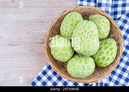 Sugar apples or custard apples in a wooden weave basket on wooden table. Stock Photo