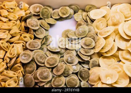 From above closeup of various types of handmade Italian ravioli arranged on white table Stock Photo