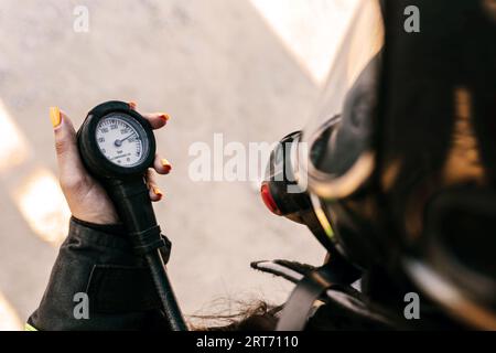 From above of crop female firefighter in self breath apparatus with alarm device in hand under sunlight Stock Photo