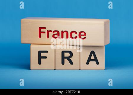 France and FRA symbol. Concept words France and FRA on wooden blocks.  English name and abbreviation of country name. Copy space.3D rendering on blue Stock Photo