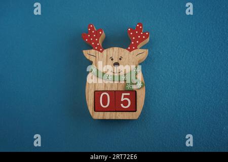 Festive wooden deer with Viva Magenta cubes 05 on blue background close-up top view. Christmas concept of date or time Stock Photo