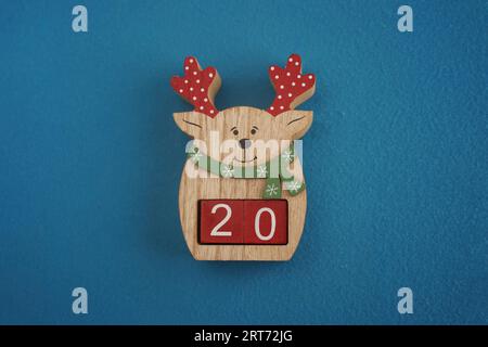 Festive wooden deer with Viva Magenta cubes 20 on blue background close-up top view. Christmas concept of date or time Stock Photo