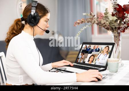 Young having conversation with her colleagues during video call Stock Photo