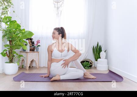 Woman in sportswear doing yoga exercise while working out at home. Sports concept. Stock Photo