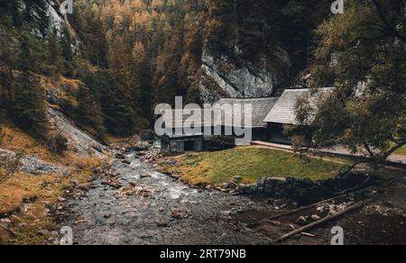 Photo of a beautiful wooden cabin with river in the forest from above - Mlyny Oblazy (Slovakia) - taken by drone. Old wooden mill with rocks on backgr Stock Photo