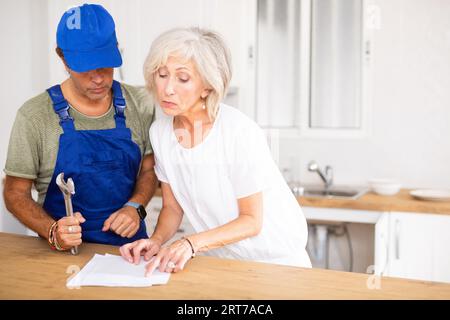 Woman homeowner and plumber discussing contract documents Stock Photo