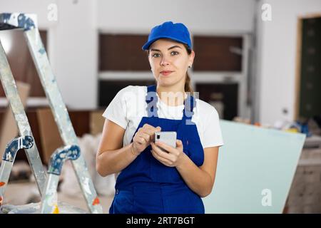 Female construction worker using smartphone in apartment Stock Photo