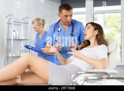 Focused physician talking to young female patient in clinic Stock Photo
