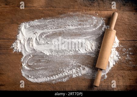 Rolling pin and flour as background  on wooden cutting board or kitchen table, top view, copy space. Baking or cooking concept. Stock Photo