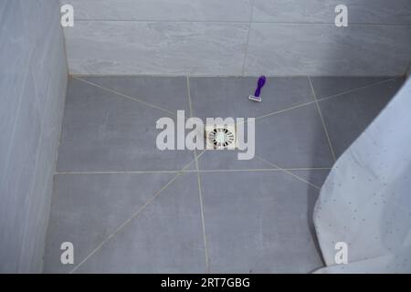Hair in the shower sink and razor on the floor. Clogged sink after hair Stock Photo