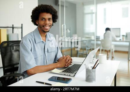 Portrait of smiling Black project manager working on laptop in office Stock Photo