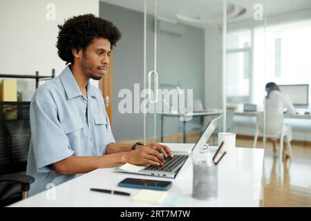 Serious young Black project manager working on laptop in modern office Stock Photo