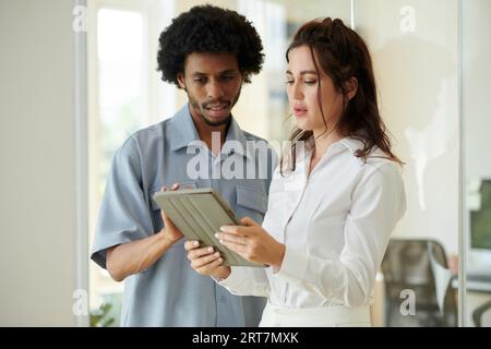 Frowning business people discussing report on tablet computer Stock Photo