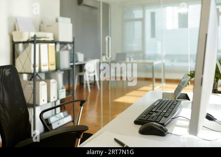 Empty chair next to computer desk in office of modern company Stock Photo