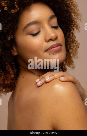 Biracial woman with dark curly hair smiling with eyes closed and hand on shoulder Stock Photo