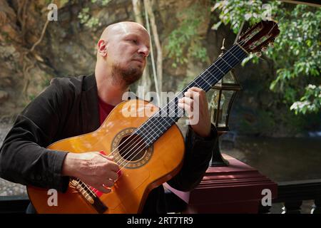 Handsome guy enjoying leisure time playing the guitar in the wild Stock Photo
