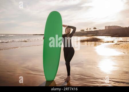 Beautiful young female surfer posing with her surfboard at the beach Stock Photo