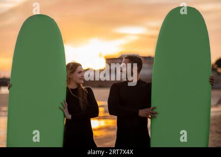 Portrait Of Romantic Young Man And Woman With Surfboards Posing On Beach Stock Photo