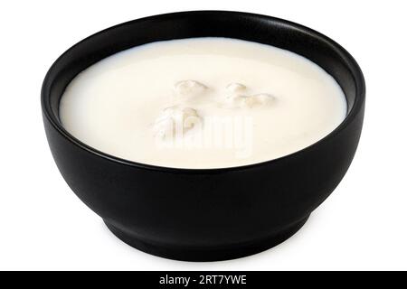 Milk with kefir grains in a black ceramic bowl isolated on white. Stock Photo