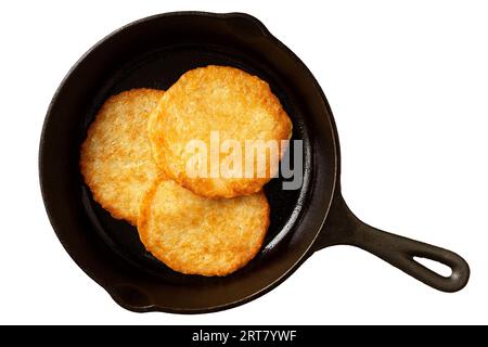 Three potato pancakes on a cast iron frying pan isolated on white. Top view. Stock Photo