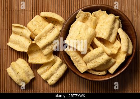 Lentil chips in a rustic wood bowl next to a pile of lentil chips on bamboo matt. Top view. Stock Photo