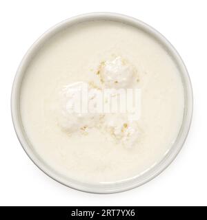 Milk with kefir grains in a white ceramic bowl isolated on white. Top view. Stock Photo