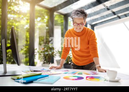 Stylish mature lady clothing designer using computer Stock Photo