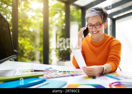 Middle aged creative woman designer have phone call with client Stock Photo