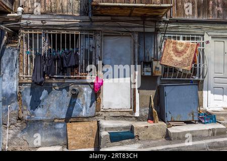 A house façade in Chugureti, Tbilisi, Georgia: laundry is drying on barred windows, a patterned rug is airing on the balustrade, and utility pipes run exposed along the wall. The scene depicts everyday living conditions in one of the older, unrenovated residential neighbourhoods of the Georgian capital. Kumisi Street, Chughureti, Kveda Chugureti, Chugureti District, Tbilisi, 0102, Georgia Stock Photo