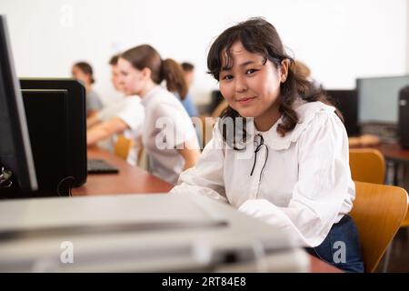Concentrated Asian female student using PC and studying computer science in the classroom Stock Photo