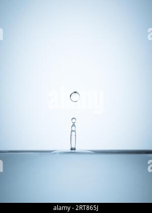 Detail of water drops falling hitting the surface of water isolated on white background Stock Photo