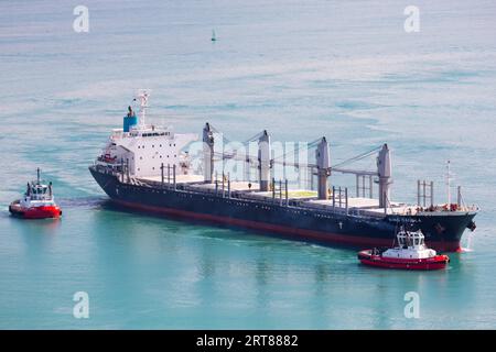 NAPIER, NEW ZEALAND -SEPTEMBER 30, 2017: Tug boats guide a shipping container into the Port of Napier in New Zealand Stock Photo