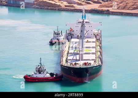 NAPIER, NEW ZEALAND -SEPTEMBER 30, 2017: Tug boats guide a shipping container into the Port of Napier in New Zealand Stock Photo