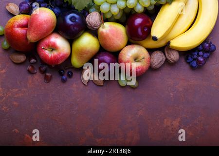 Ripe fruits on rustic background with copyspace. Banana, pear, plum, peach, apples, red and white grapes Stock Photo