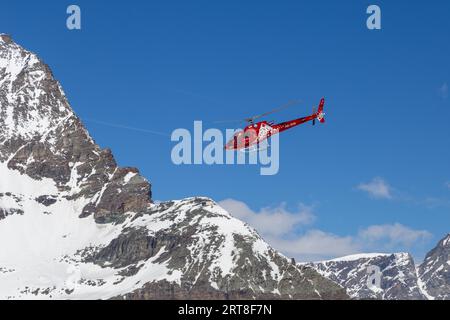 Zermatt, Switzerland, April 13, 2017: A red rescue helicopter flying in the Matterhorn Area in the Swiss Alps Stock Photo