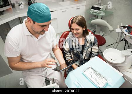 Dentist communicates with patient in dental office using digital tablet. Stock Photo