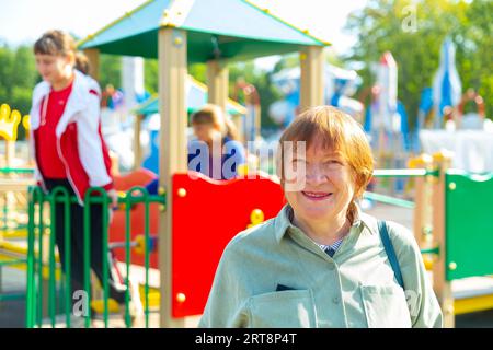 Grandmother walks with her grandchildren on playground Stock Photo