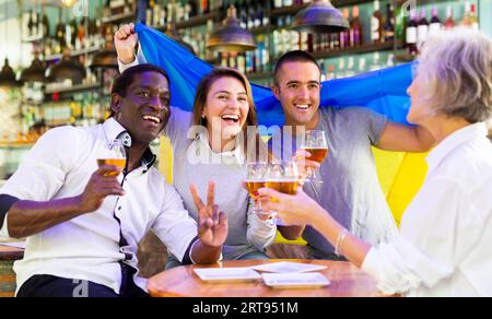 Happy fans celebrating the victory of Ukrainian team in bar Stock Photo